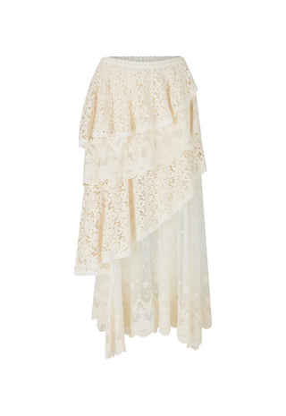 A woman wearing a white lace slip dress with sheer panels and white pointed-toe heels