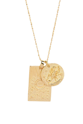 close-up-front-view-of-spell-s-scorpio-stargazer-zodiac-necklace-charms-one-charm-is-of-a-rectangular-shape-and-features-a-sun-with-stars-while-the-other-charm-is-circular-and-features-the-zodiac-label-and-icon